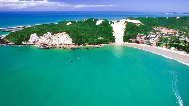 An aerial view of a coastal area with a beach, a small town, and a forested hill. - NYC Park Ave Beach Apt •3BR • Private Pool • Oceanview in Ponta Negra Natal (Ponta Negra Natal)