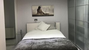Et moderne soveværelse med seng, et billede og en glasvæg.