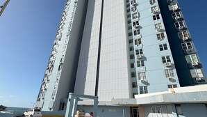 A high-rise residential building with multiple floors, a central elevator shaft, and a parking area with a yellow curb.