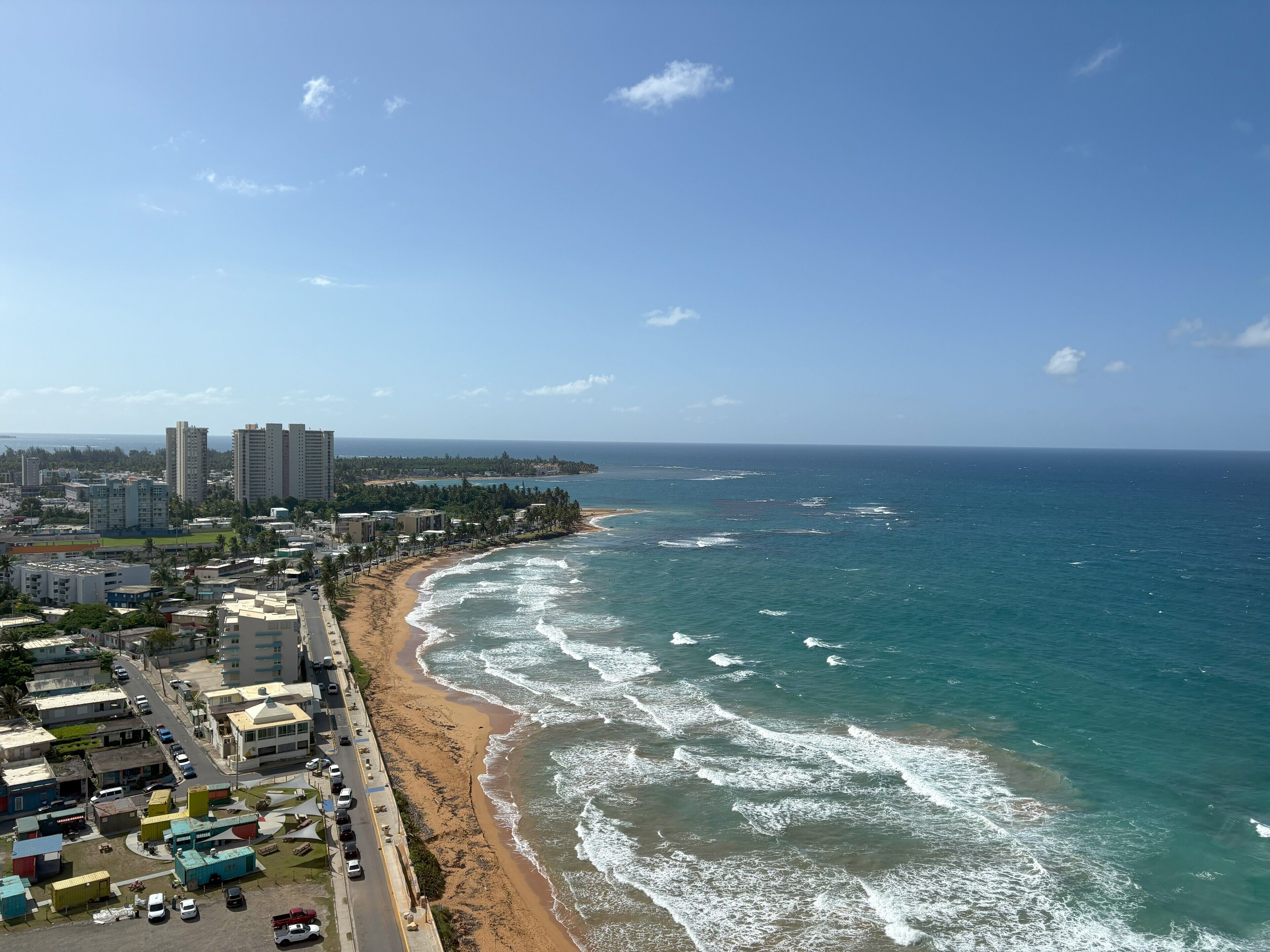 A coastal cityscape with a beach, high-rise buildings, and a clear sky.
