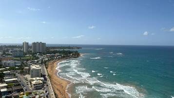 A coastal cityscape with a beach, high-rise buildings, and a clear sky.