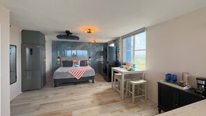 A modern bedroom with a large bed, a built-in wardrobe, and a small kitchenette.