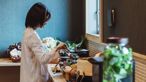 A person preparing food in a kitchen with a counter, a bowl of vegetables, and a bottle of oil. - BedandVegetable Kahoku (Kahoku)