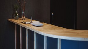 A reception desk with a wooden surface, a white plate, a glass, and a vase with branches. - BedandVegetable Kahoku (Kahoku)