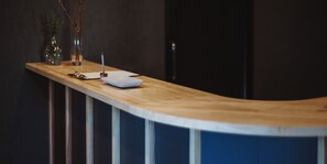 A reception desk with a wooden surface, a white plate, a glass, and a vase with branches. - BedandVegetable Kahoku (Kahoku)