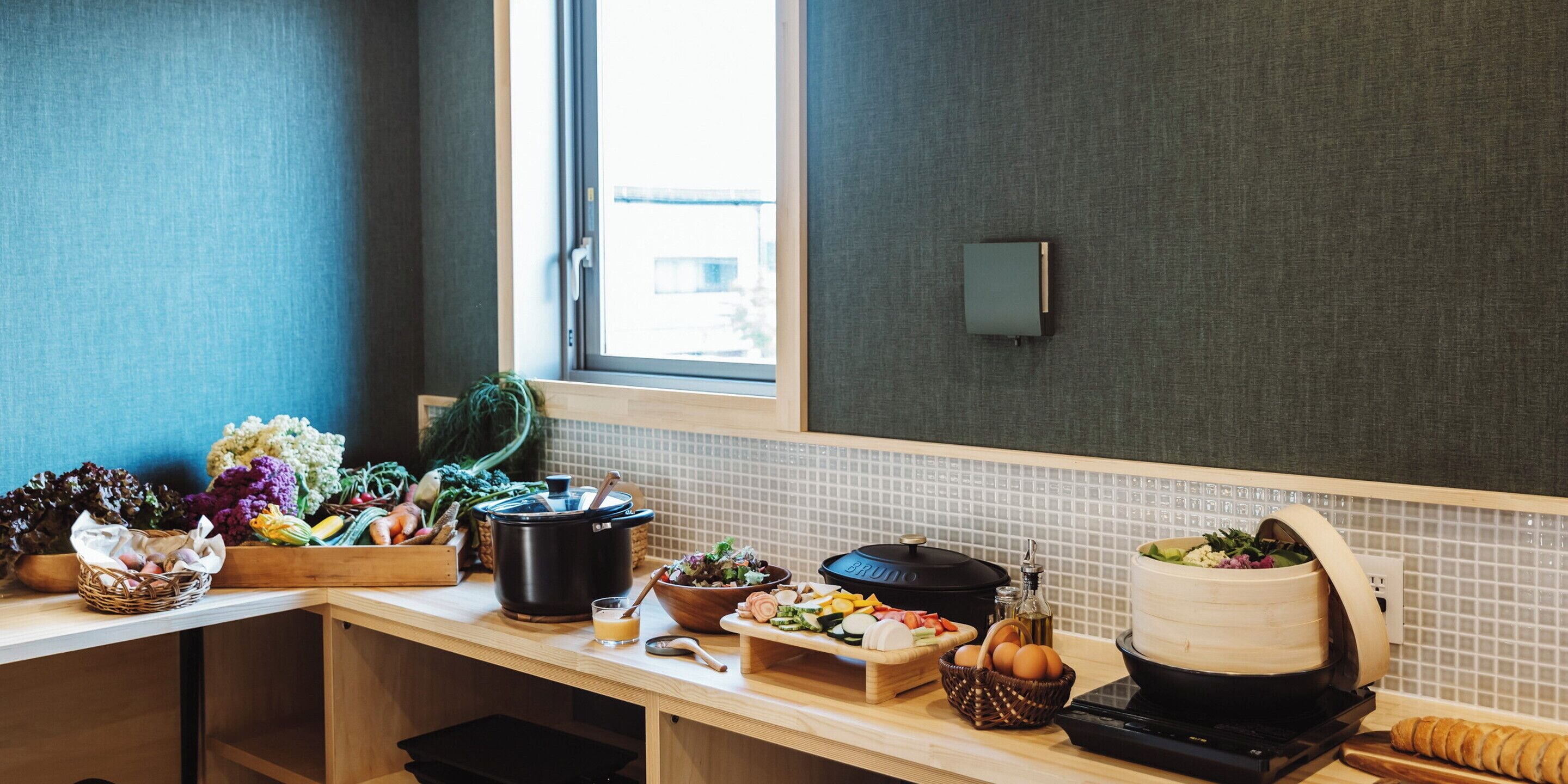A kitchen with a variety of fresh produce, a slow cooker, and a bread machine on the counter.