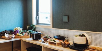 A kitchen with a variety of fresh produce, a slow cooker, and a bread machine on the counter.