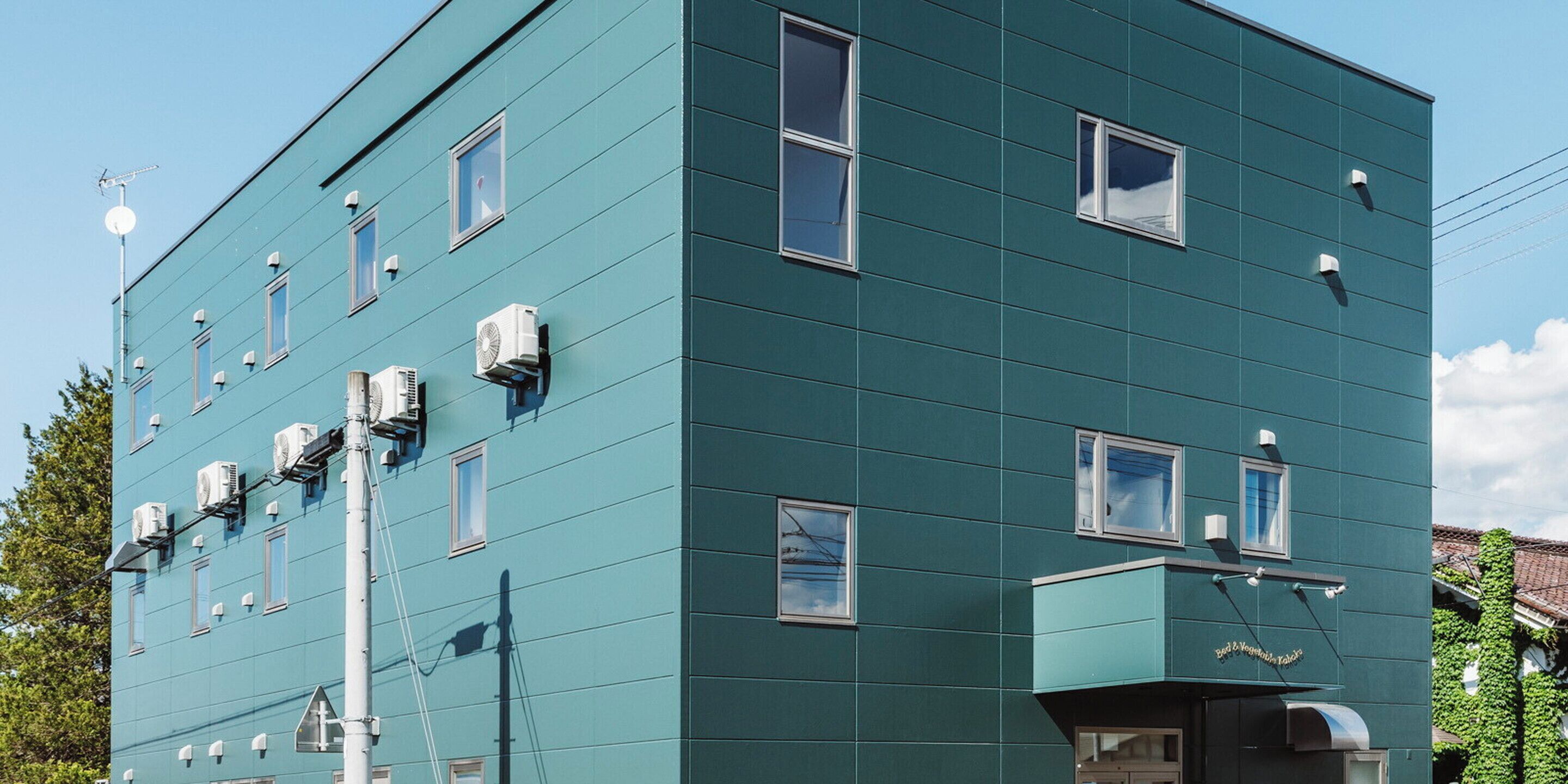A multi-story building with air conditioning units, a visible antenna, and a clear sky.