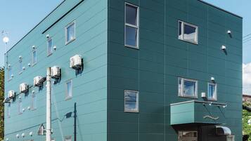 A multi-story building with air conditioning units, a visible antenna, and a clear sky.