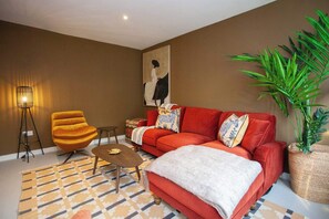 A modern living room with a red sofa, a yellow armchair, a coffee table, a floor lamp, and a large painting on the wall. - Newly Renovated House in Popular Location (Glasgow)
