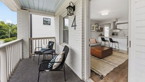 A covered patio with two chairs and a table, a kitchen area with a countertop and chairs, and a number '4' on the wall. - Optimist Abode 4: Chic Stay in the <3 of CLT with Greenway Access (Charlotte)
