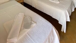 A hotel room with three single beds, a blue wall, an air conditioner, and a tiled floor. - Saray Otel (Kas)