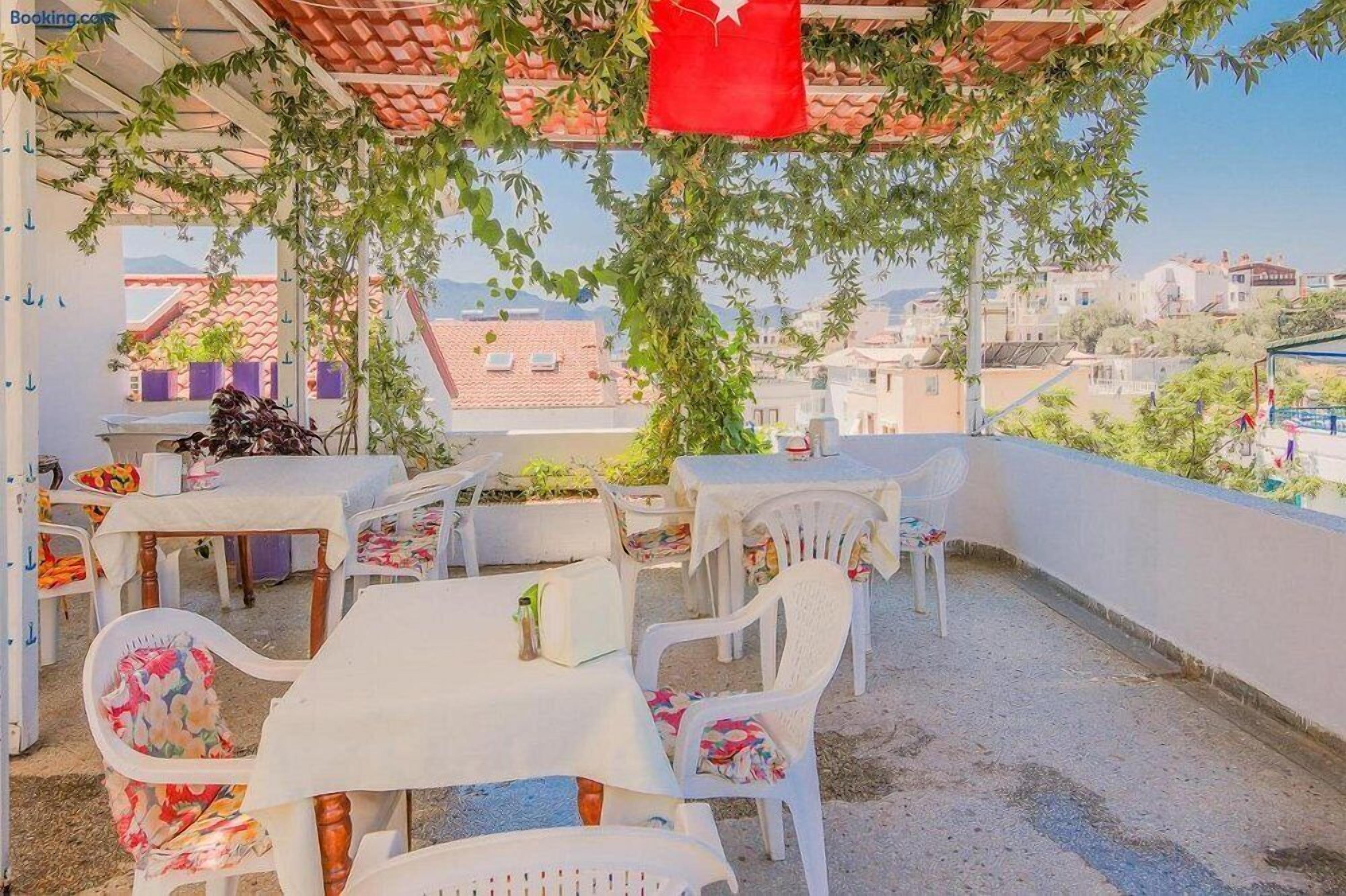 An outdoor patio area with tables and chairs, a red hanging object, and a view of buildings in the background.