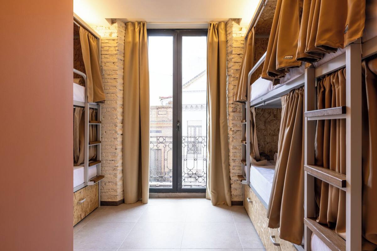 A narrow room with a large sliding glass door leading to a balcony, featuring a brick wall and wooden shelves on both sides.