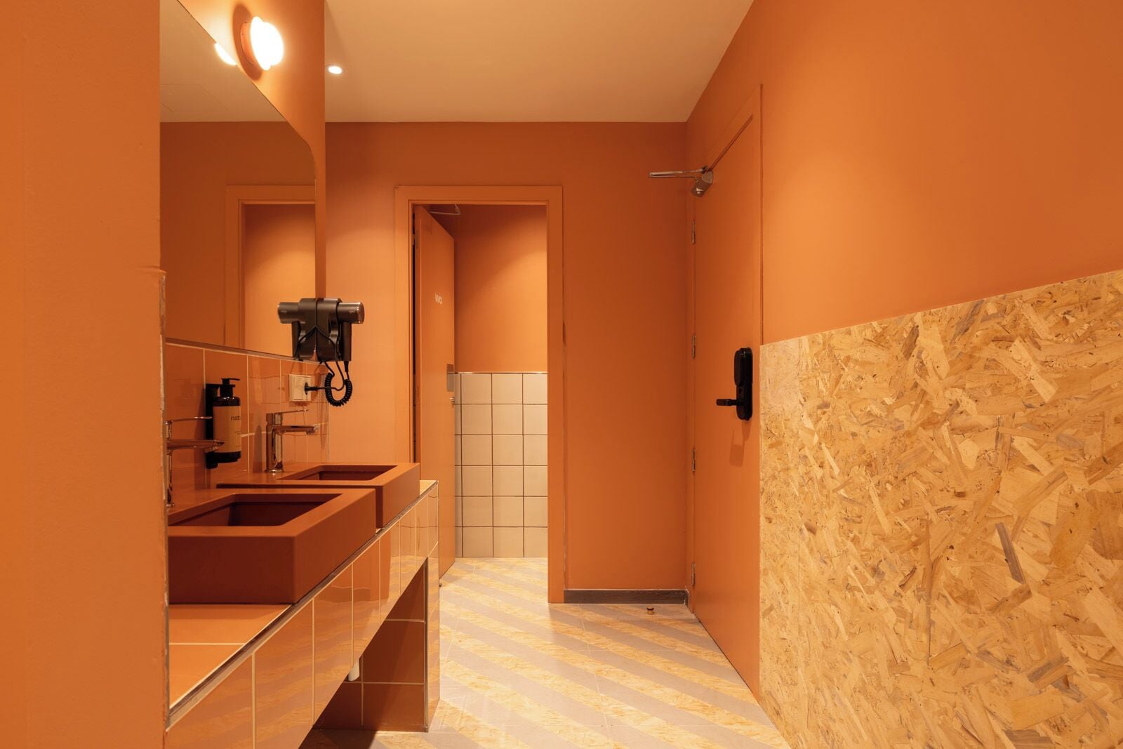 Un baño moderno con un espejo grande, lavamanos dobles y zona de ducha.