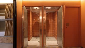 A modern elevator with glass doors, a tiled interior, and a carpeted floor.