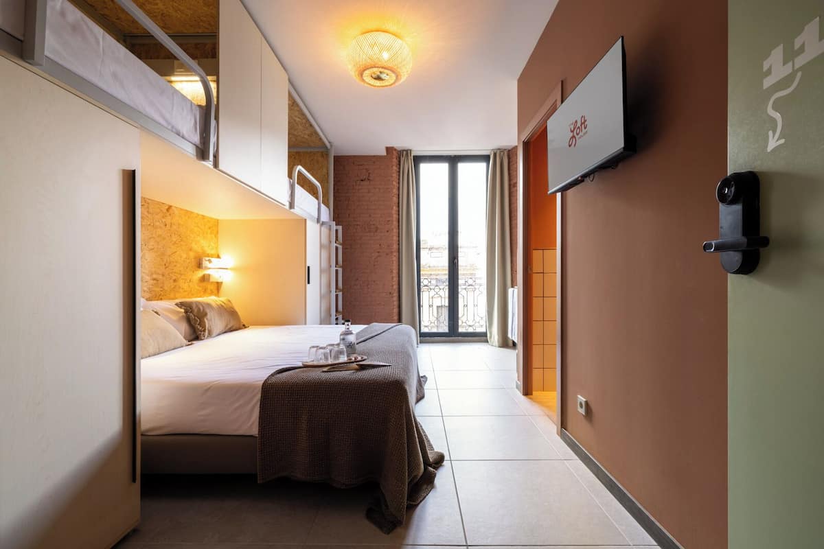 A compact hotel room with a bed, bedside table, and a television mounted on the wall.