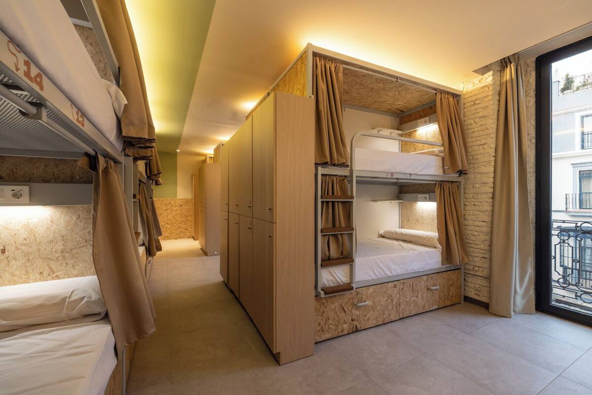 A compact hotel room with bunk beds, wooden wardrobe, and a balcony with a view.