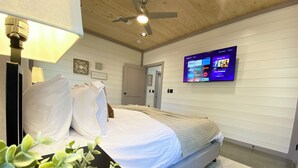 Ein Schlafzimmer mit einem Bett, einem an der Wand montierten Fernseher und einem Deckenventilator.