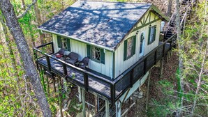 A cabin with a balcony, surrounded by trees.