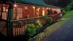 A log cabin with a porch, outdoor seating, and an American flag. - *Gorgeous 3BD Cabin Near LAKE w/ Pool Access* (Sevierville)