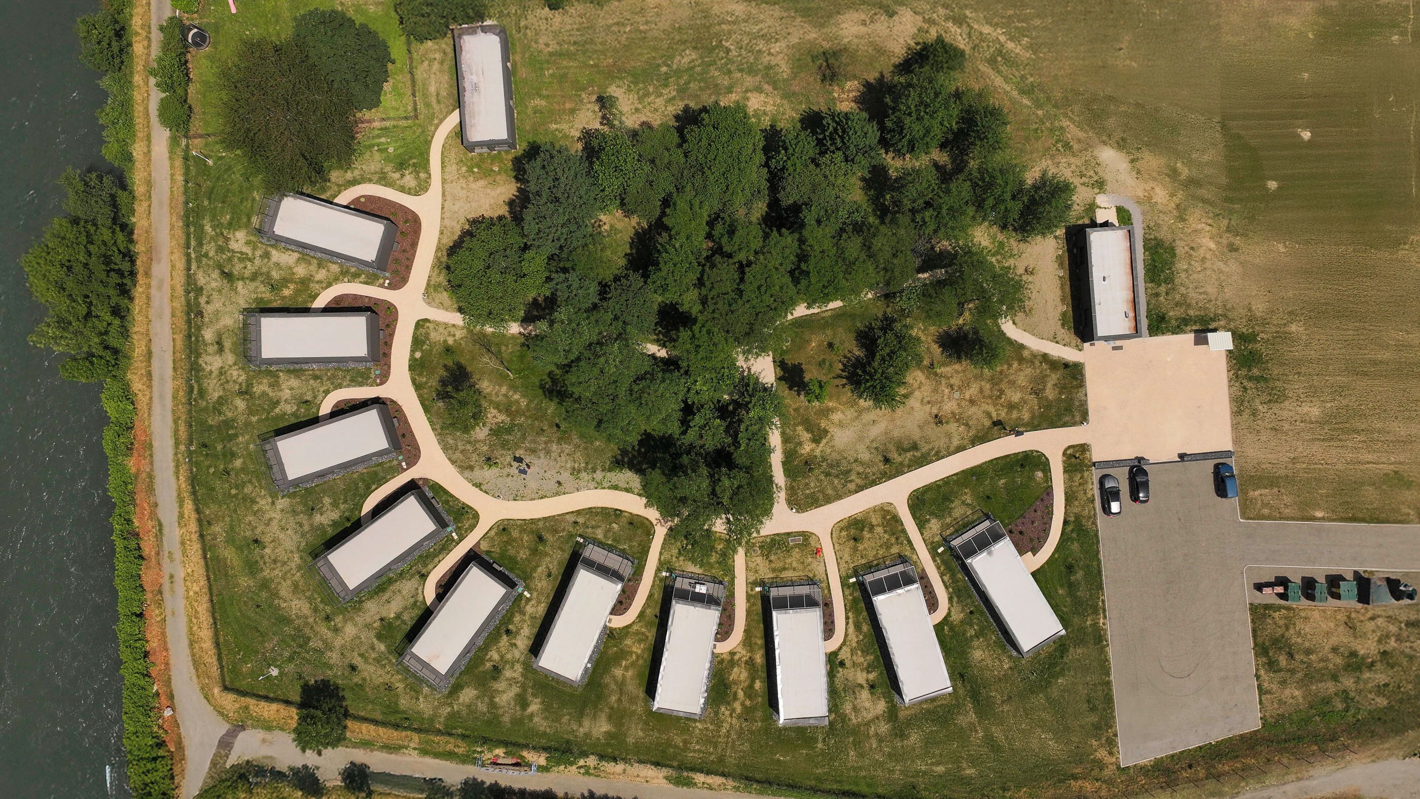 Vista aérea de una propiedad con varios edificios rectangulares dispuestos en semicírculo alrededor de un área verde central.