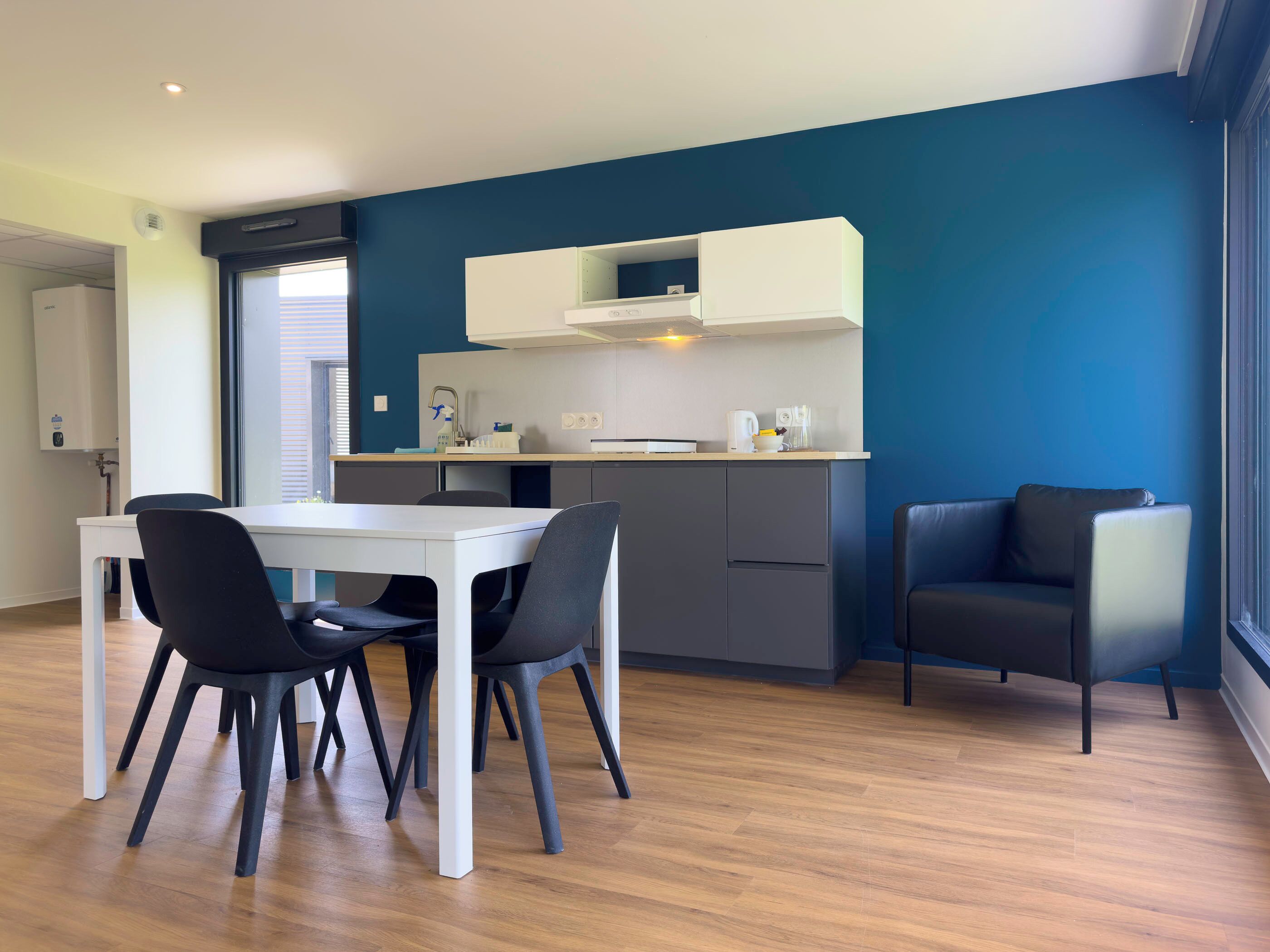 Een moderne keuken met witte kasten, een eettafel met stoelen en uitzicht op het groen.