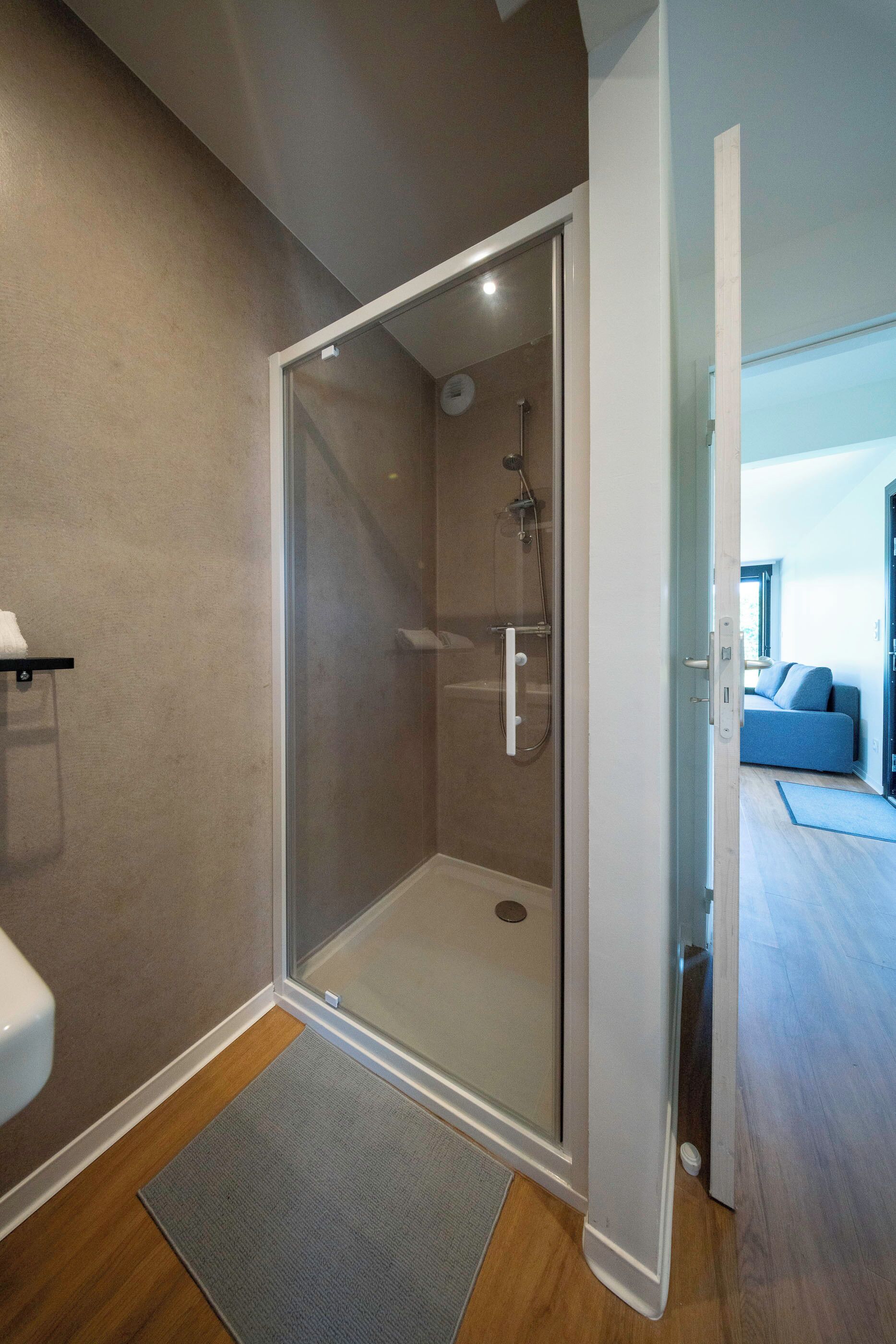 Une salle de bain moderne avec une douche à parois de verre, des toilettes et un porte-serviettes apparent.
