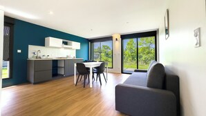Un apartamento moderno con cocina, comedor y un amplio ventanal con vistas a zonas verdes.