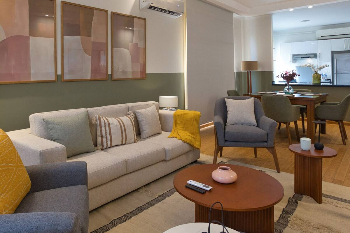 Een moderne woonkamer met een bank, fauteuils, een salontafel en een eethoek met stoelen en een tafel.