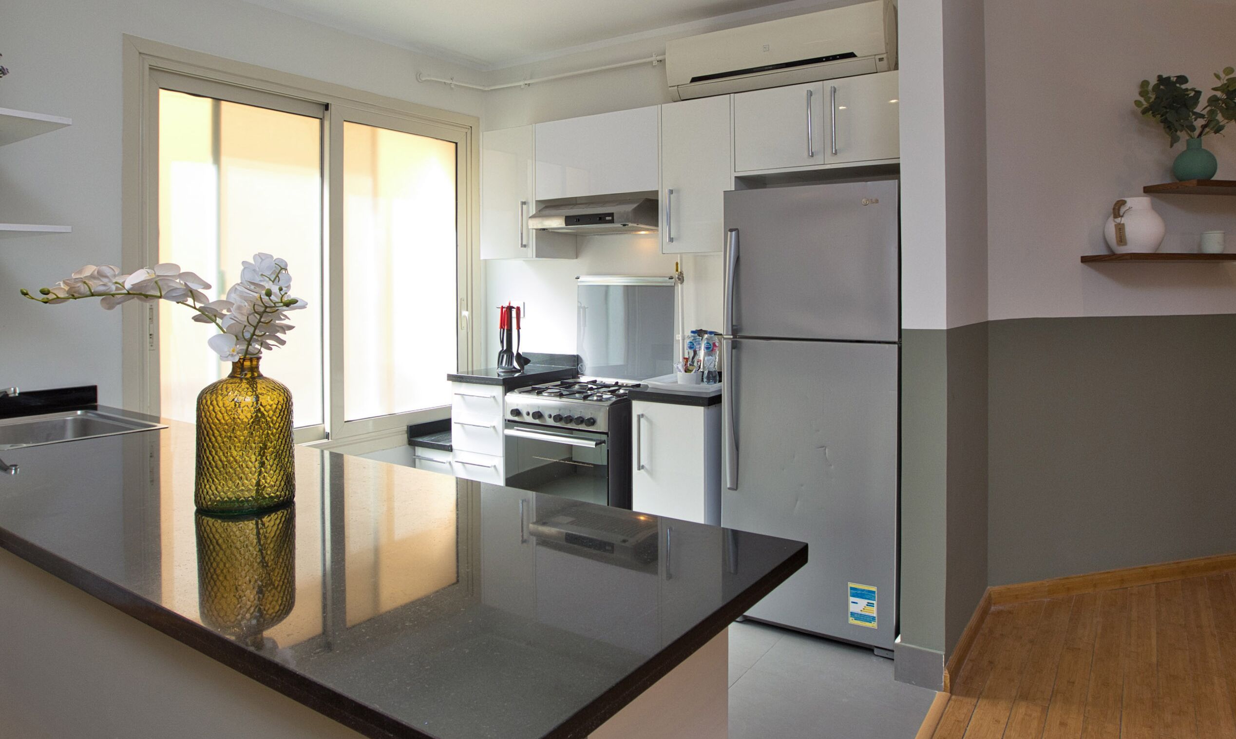 Une cuisine moderne avec des armoires blanches, un réfrigérateur en acier inoxydable, un four encastré et une cuisinière à gaz.