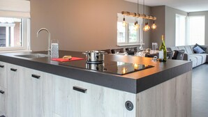 A modern kitchen with a large island, stainless steel appliances, and a dining area with a sofa.