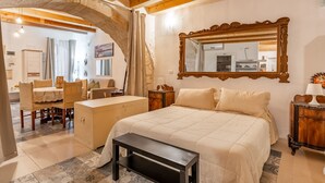 Un dormitorio con una cama, un banco de madera, un aparador, un escritorio y una silla.