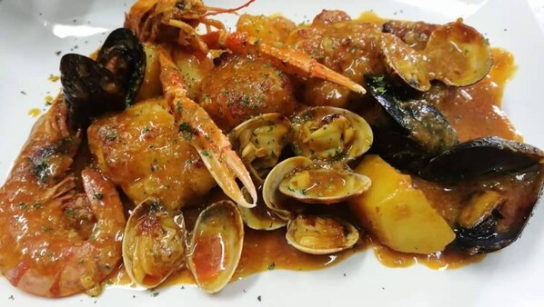 A seafood dish with mussels, clams, and shrimp in a tomato-based sauce.