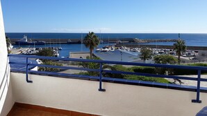 En balkon med udsigt over en lysthavn og havet.