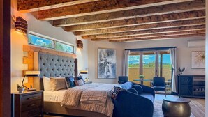 A bedroom with a large bed, wooden ceiling beams, a view of the outdoors, and a modern design. - Indoor Pool and Pickleball Estate (Santa Fe)