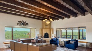 A spacious living room with a large sectional sofa, a blue armchair, and a fireplace. - Indoor Pool and Pickleball Estate (Santa Fe)