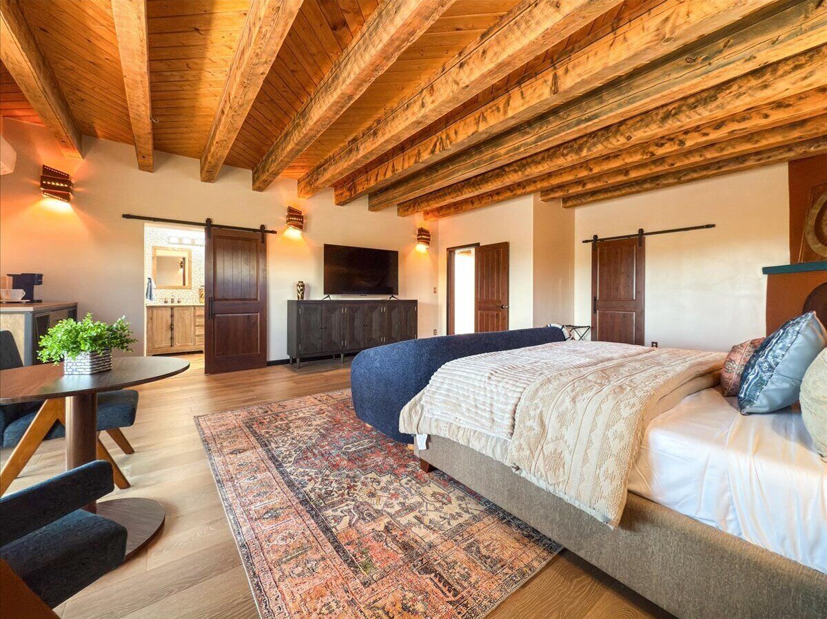 A spacious bedroom with a large bed, a dining area with a table and chairs, and a kitchen area with cabinets and a TV.