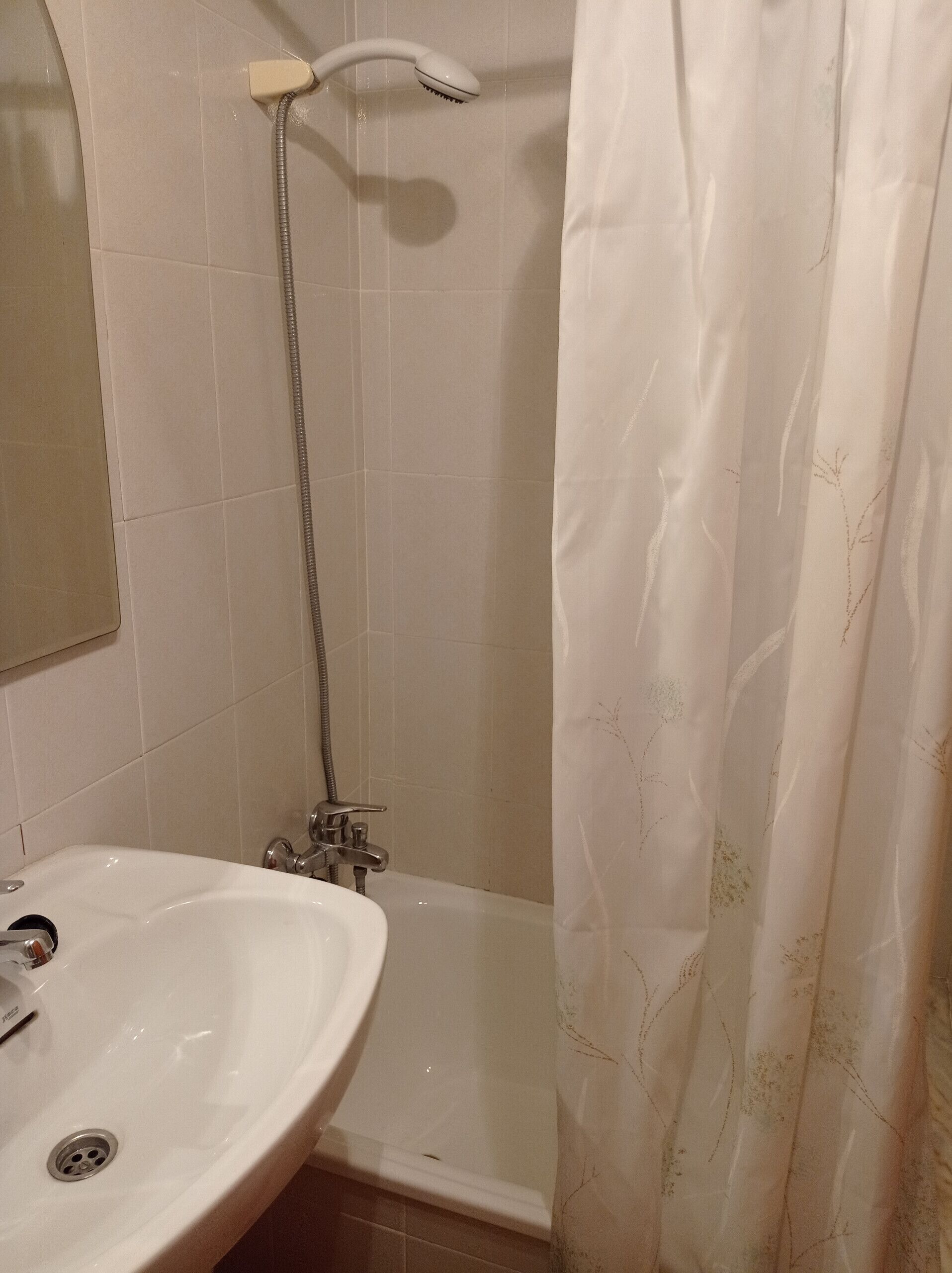 A bathroom with a shower, a sink, and a mirror.