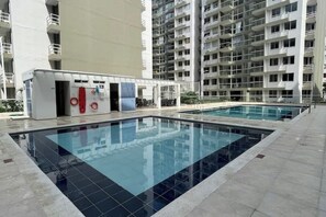 Área de piscina com um edifício moderno ao fundo.
