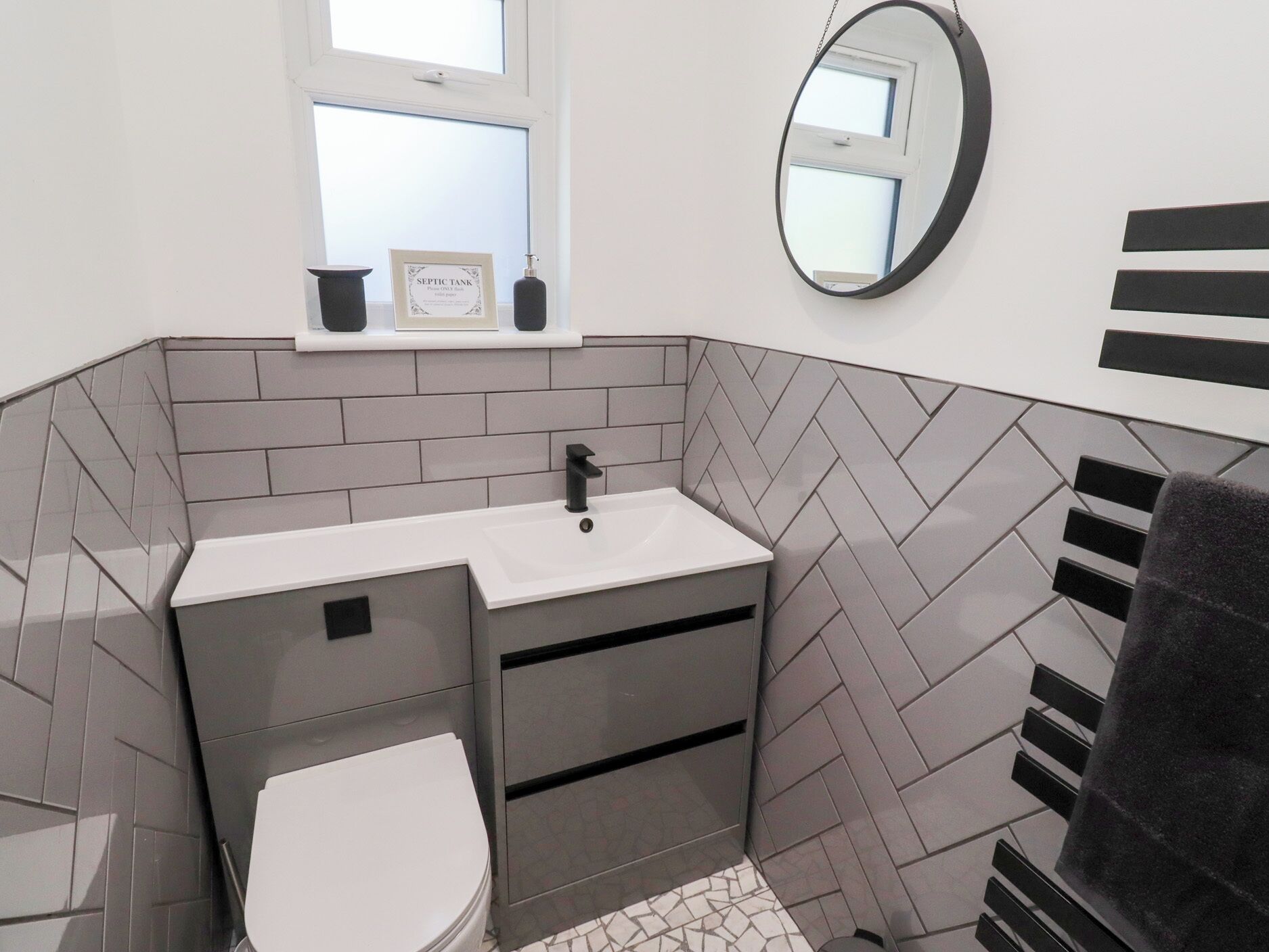 Un baño moderno con un lavamanos blanco, un inodoro y un espejo.