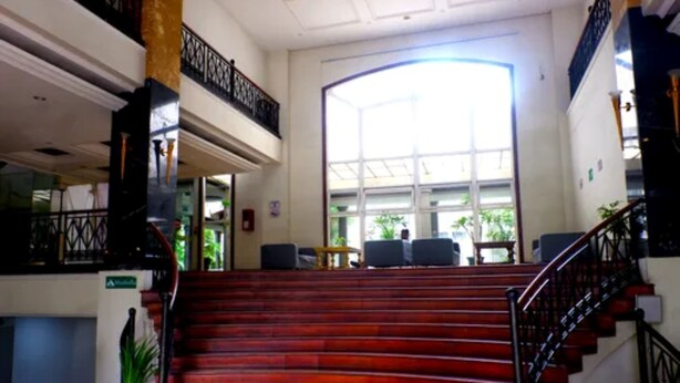 A grand staircase leading to a balcony with a view of greenery outside. - Caspella Suites Hotel Kemayoran (Jakarta)