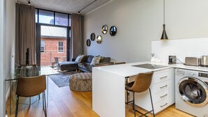 A compact living space with a kitchenette, a dining area, and a laundry area. - The Docklands Luxury Apartments (Cape Town)