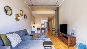 A modern living room with a sofa, ottoman, and a TV stand. - The Docklands Luxury Apartments (Cape Town)