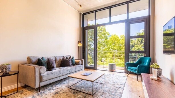 A modern living room with a sofa, coffee table, and a blue armchair. - The Docklands Luxury Apartments (Cape Town)