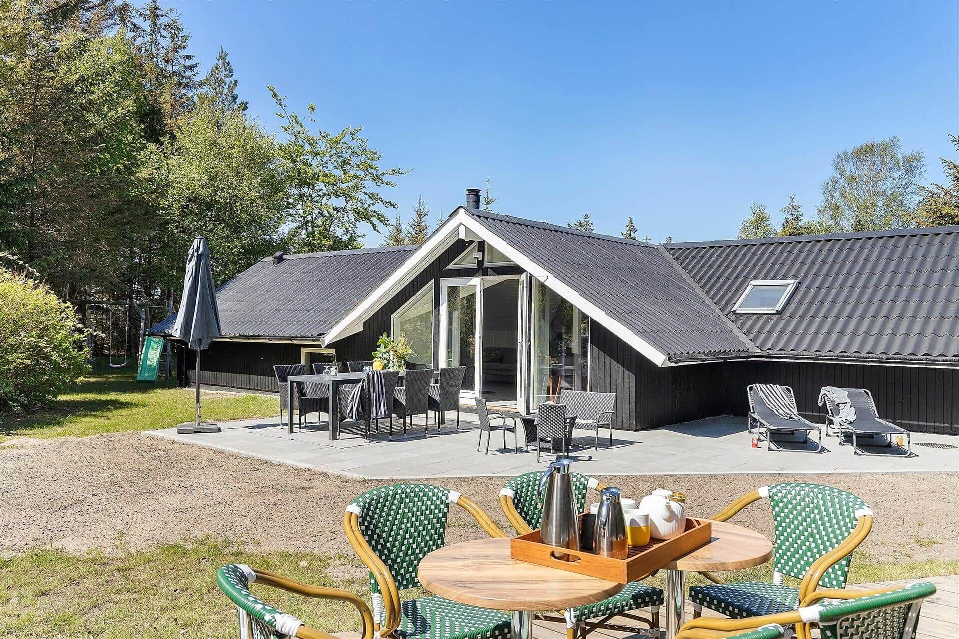 Een moderne buitenruimte met zitmeubels, een tafel, stoelen, een barbecue en een overdekte parasol.