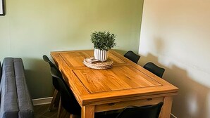 Une table de salle à manger en bois, avec six chaises, une plante en pot et un dessous de verre en fibres tressées.