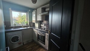 Une cuisine compacte équipée d’un lave-linge, d’une cuisinière et d’un évier.