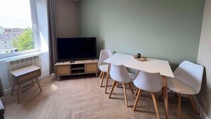Een moderne eetruimte met een televisie, witte stoelen en een tafel.