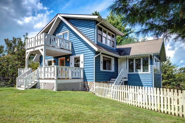 A two-story house with a balcony, a front porch, and a picket fence.